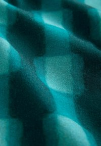 Țesătură de culoare teal cu o textură moale, prezentând un model de carouri estompat în nuanțe variate. Lumina se reflectă subtil, creând adâncime.