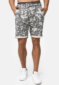 Pantalones cortos gris floral hechos de tela con patrones de hojas blancas. El diseño incluye una cinturilla con cordón y dobladillos enrollados.