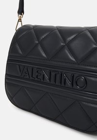 Borsa a tracolla in pelle trapuntata nera con logo "VALENTINO" in rilievo, forma strutturata e tracolla removibile con finiture dorate.