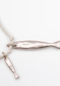 To sølvfisk-formede vedhæng på en beige snor, den ene større med "Massimo Dutti" indgraveret, begge glatte og metaliske.