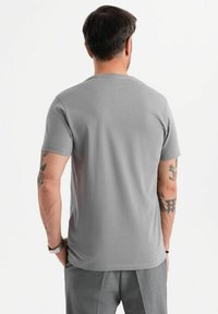 Šedé bavlněné tričko s krátkým rukávem, klasickým kulatým výstřihem a hladkým povrchem, zobrazené ze zadní strany, bez log.