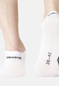 Chaussettes blanches invisibles portées sur des pieds, avec le logo noir "Umbro" sur le talon et la taille "38-42" imprimée sur la semelle sur un fond uni.