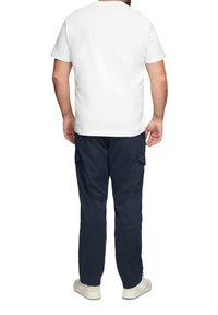 Witte katoenen T-shirt met een ronde hals, gecombineerd met marineblauwe cargobroek met zijzakken en een taps toelopend ontwerp.