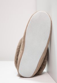 Brown suede slipper with a plush, textured exterior and a white rubber sole. The sole is flat and slightly rounded at the toe.