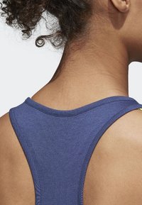 Mörkblå linne med racerback-design, ribbad textur och kontrasterande gula detaljer vid axelsömmarna.