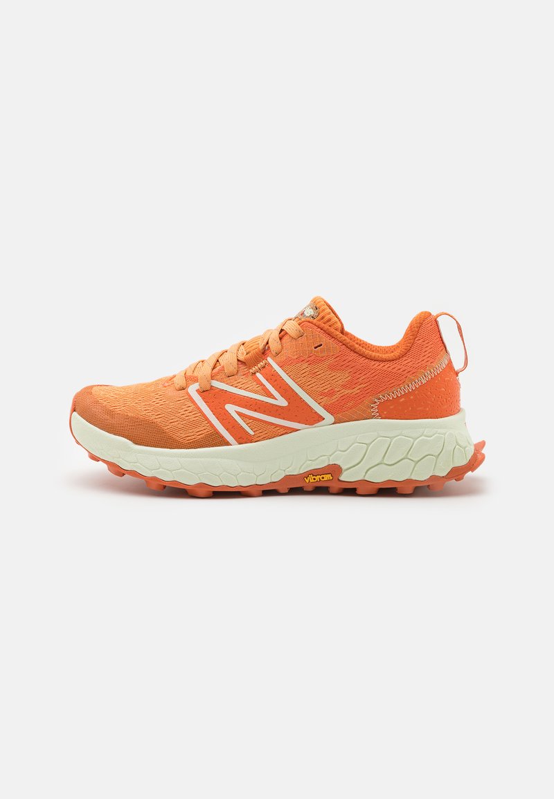 Orange running shoe with white sole, thick tread, pull tab at heel, lace-up closure, and white "N" logo on the side.