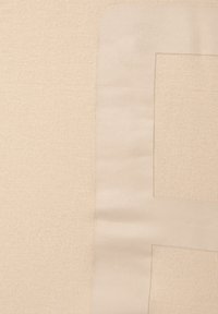 Tissu beige avec un mélange de textures tricotées et lisses, présentant un détail de couture subtil en forme de rectangle dans le coin supérieur.