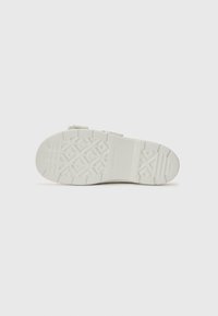 Hvit gummi sneaker med teksturert s�åle som har et geometrisk mønster og justerbare stropper. Glatt overmateriale uten logoer.