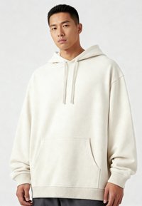 Tejfehér kapucnis pulóver elülső zsebbel, laza szabású, bordás mandzsettákkal és texturált felülettel. Simább felület, finom pöttyökkel.