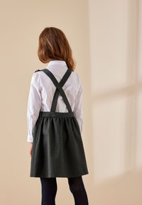 Tumehall kivikeskkleit ristkäevõruga valge pika varrukaga särk. Seeliku osa on kroogitud, pakkudes täiskujundust.