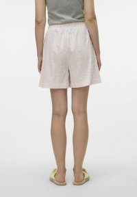 Lichtroze shorts met een geruit patroon, een elastische tailleband, van gemiddelde dijlengte en een soepele textuur. Gepaard met gele instappers.