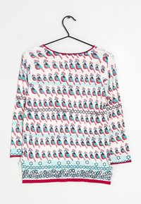 Losse, lange mouwen top met een kleurrijke vogelprint, voornamelijk in rood- en tinten blauw, met een ronde halslijn en zijsplitten.