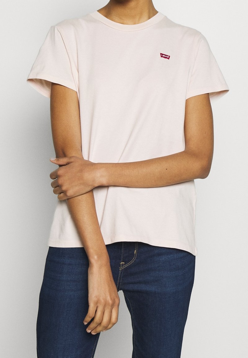 Ljusrosa t-shirt med kort ärm i mjuk bomull, rund halsringning och en liten röd Levi's-logotyp på vänster bröst. Avslappnad passform.