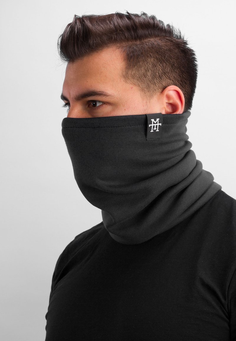 Black neck gaiter made of soft fabric, designed to fit snugly around the neck. Features a small logo tag on the side.