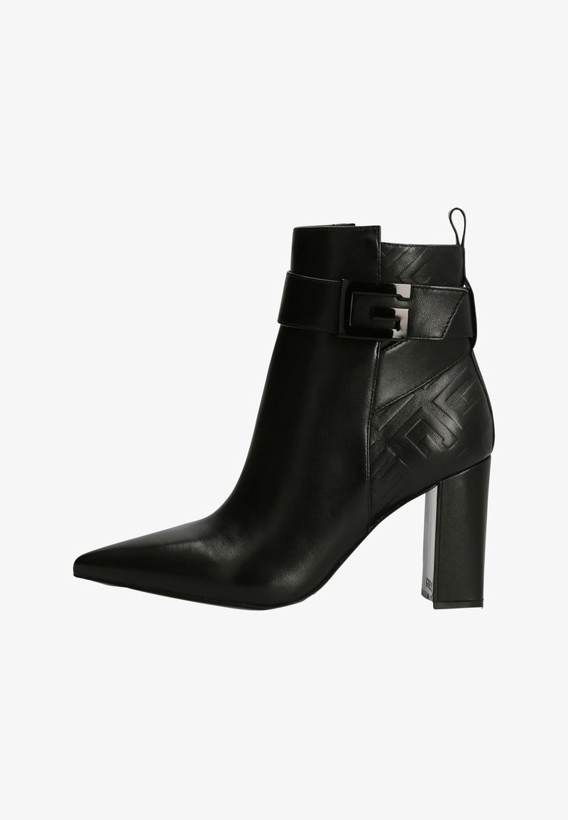 Bottine en cuir noir à bout pointu, talon bloc, sangle décorative avec boucle, et motif géométrique embossé sur le côté.