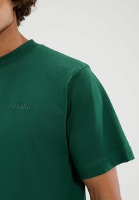 Groene katoenen T-shirt met een ronde hals, korte mouwen en een subtiel reliëflogo op de borst; gladde stof en een klassieke pasvorm.
