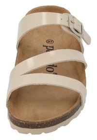 Beige slidessandal med tre blanka remmar, justerbar spänne och en fotbädd av kork. Mjuk texturerad innersula med en robust, kontrasterande sula.