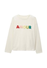 Chemise à manches longues crème avec le mot "AMOUR" en relief et multicolore en tissu doux. Coupe décontractée avec un col rond et sans coutures visibles.