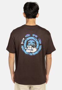 Bruine katoenen t-shirt met een kleurraf cartoonafbeelding op de achterkant, waarop een opgerolde hond te zien is, omringd door blauwe en paarse ontwerpen.