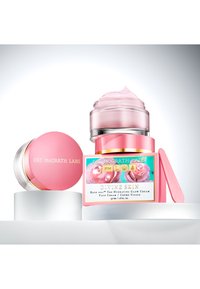 Pink jar with a transparent lid and a pump, featuring floral artwork and gold accents. Second pink container with a matching lid.