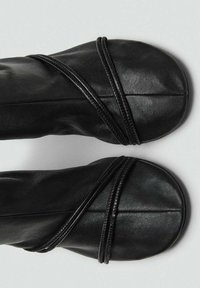 Ballerines en cuir noir avec des accents tressés entrecroisés sur le dessus. Bout rond et texture lisse, design minimaliste.