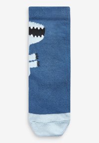 Calcetín azul con una textura suave que presenta un diseño de una criatura blanca caricaturesca con una boca negra. Puño azul claro en la parte superior.