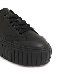 Zapatillas negras de plataforma con acabado mate, puntera redonda y suela gruesa estriada. Presenta cordones negros y ojales de metal para un ajuste seguro.