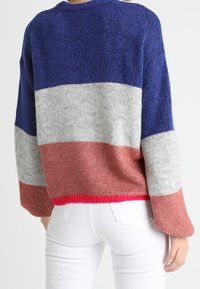 Strickpullover mit color-block Design in Marineblau, Grau, Pink und Rot gestreift. Strukturiertes Material, lockere Passform und abgesteppte Schultern.