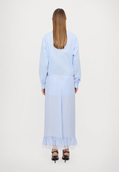 Blusa azzurro chiaro con maniche lunghe abbinata a una lunga gonna coordinata con bordo in pizzo all'orlo. Tessuto morbido, vestibilità rilassata, senza motivi visibili.