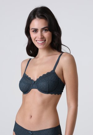 Reggiseno in pizzo blu scuro con bordi smerlati, supporto con ferretto e un piccolo dettaglio a fiocco al centro. Presenta un motivo a diamante testurizzato.