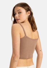 Bruin geribbeld crop top met dunne bandjes, met een nauwsluitend ontwerp en een rechte halslijn. Het materiaal lijkt zacht en rekbaar.