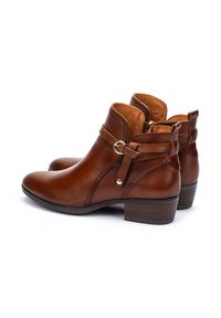 Brown leather ankle boots with a rounded toe, stacked heel, and buckle detail. Smooth finish and contrasting tan interior.