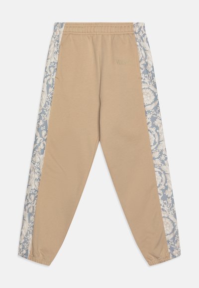 Beige sweatpants with an elastic waistband; features blue floral patterned side panels. "VERSACE" logo subtly embossed near the waistband.