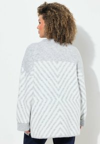 Pull pastel gris surdimensionné avec un motif en zigzag texturé. Manches côtelées et col rond. Tissu doux et duveteux apporte de la chaleur.