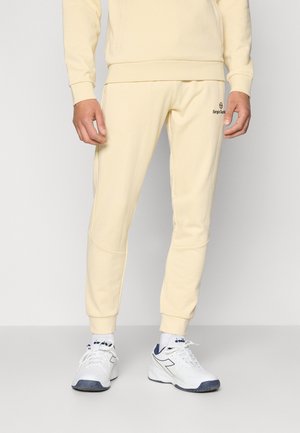 Yellow cotton tracksuit bottoms with a fitted design, tapered legs, and elasticated cuffs, featuring a logo on the left thigh.