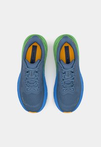 Baskets de course bleues avec des semelles vertes et bleues, présentant un dessus texturé, des accents jaunes et un design à lacets.