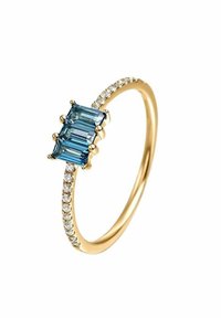 Anillo de oro con tres gemas azules rectangulares y una banda adornada con pequeñas piedras blancas, que presenta una superficie pulida y brillante.