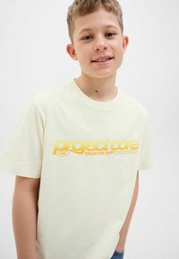 Light yellow cotton t-shirt featuring a bold yellow graphic text "project core" print and short sleeves, paired with denim jeans.