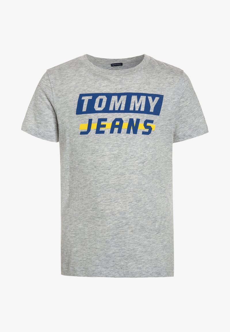 Camiseta de algodón gris con texto en azul y amarillo que dice "TOMMY JEANS". Diseño clásico de cuello redondo con mangas cortas.