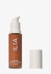 ILIA True Skin Serum Foundation in einer gefrosteten braunen Glasflasche mit einem weißen Pumpenkopf. Der Text enthält "TRUE SKIN SERUM FOUNDATION" und die Zutaten.