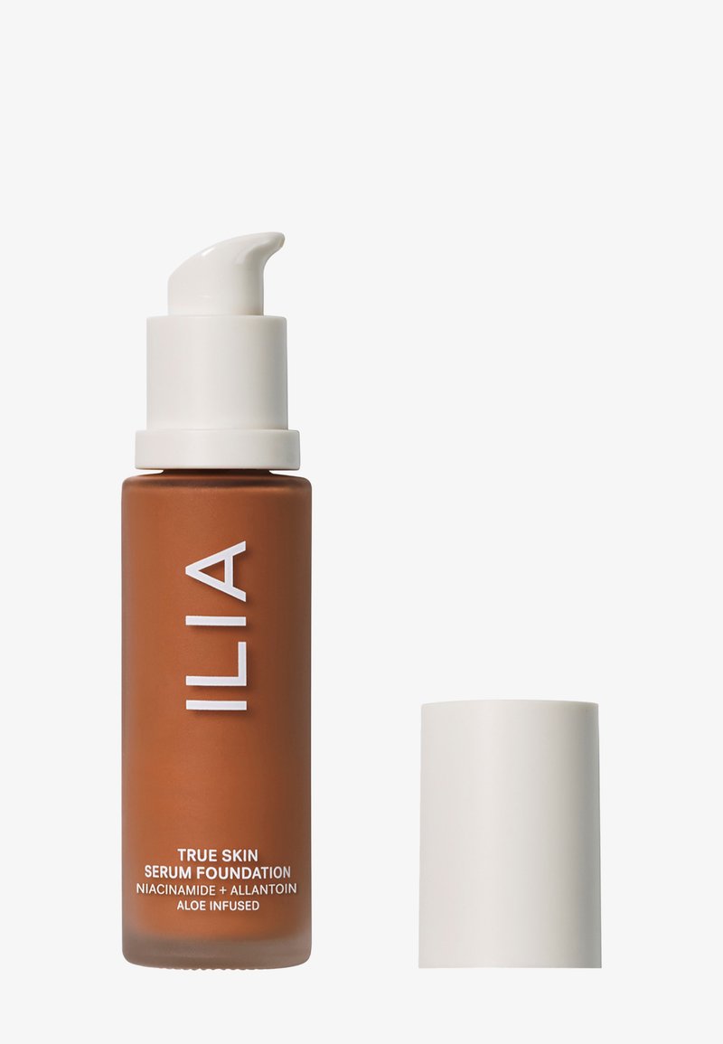 ILIA True Skin Serum Foundation in einer gefrosteten braunen Glasflasche mit einem weißen Pumpenkopf. Der Text enthält "TRUE SKIN SERUM FOUNDATION" und die Zutaten.