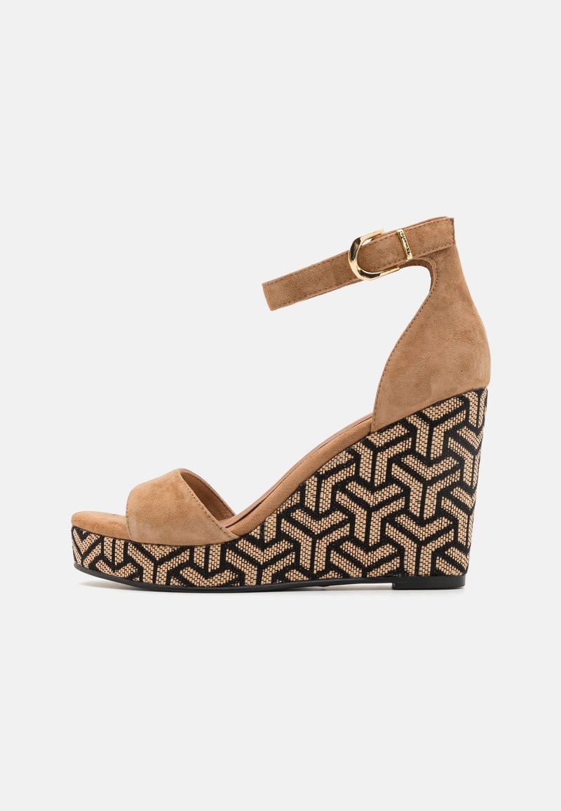 Sandales compensées en daim beige avec une bride à la cheville, présentant un motif tissé noir et beige sur la semelle compensée et une texture lisse.