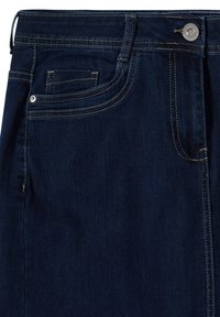 Jean en denim bleu foncé en gros plan montrant la poche avant, la petite poche à monnaie, les passants de ceinture et le bouton argenté avec couture jaune.