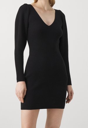 Schwarzes, geripptes Kleid mit langen Ärmeln und tiefem V-Ausschnitt. Die figurbetonte Silhouette betont die Körperform. Die strukturierte Stoffqualität sorgt für zusätzliche optische Tiefe.