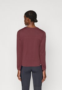 Burgundi pikkade varrukatega särk ümara kaelusega. Omab õmmeldud aktsente ja sirget allserva, valmistatud pehmest ja venivast materjalist.