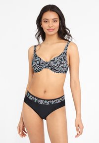 Bikini set met een zwart-wit geometrisch patroon met groene accenten. Het topje heeft beugels en verstelbare banden; de onderkant heeft een gepatternde tailleband.