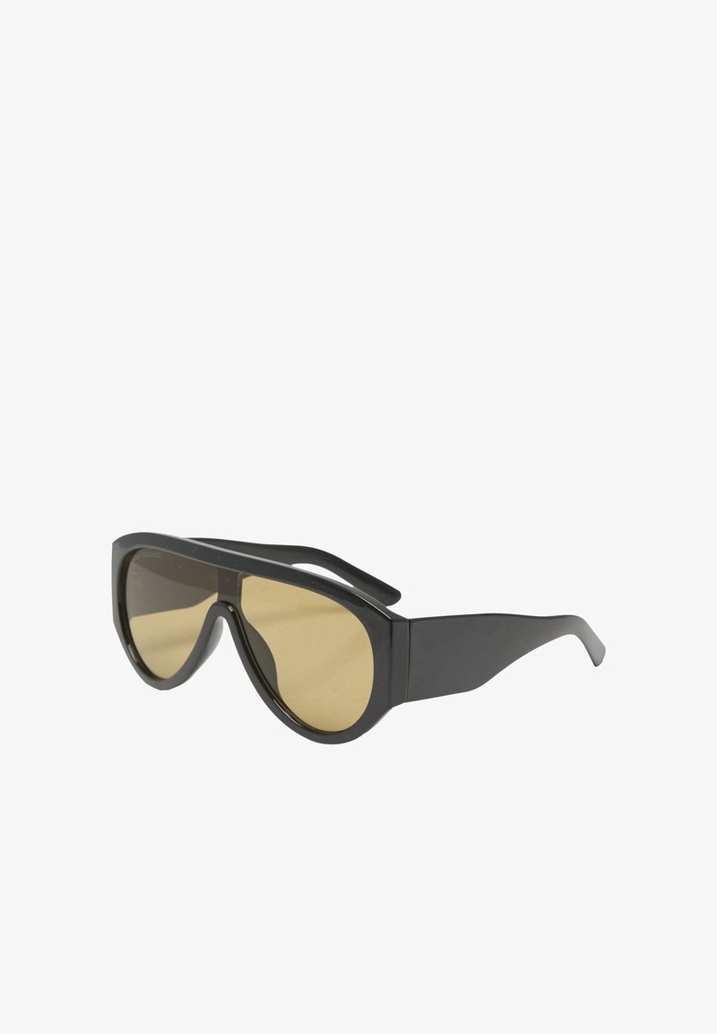 Lunettes de soleil enveloppantes noires avec de larges branches et des verres teintés jaune, inclinées pour montrer les détails de face et de côté.