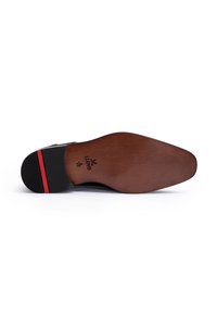 Suola di scarpa in pelle nera con finitura liscia, caratterizzata da una midsole in legno marrone e un tacco nero zigrinato con una striscia accentuata rossa.