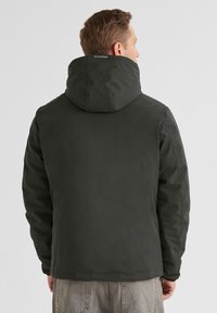 Dunkelgrüne Kapuzenjacke mit glattem, wasserdichtem Außenmaterial, wattiert für Wärme, mit einem schlichten Design und sichtbaren Nähten.