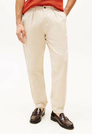 Beige plooibroek met een ontspannen pasvorm, gemaakt van lichtgewicht stof. Voorzien van een knoopsluiting en zijzakken.